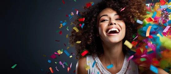 Gardinen Brazilian woman in costume at a Carnaval party, blowing confetti with curly hair. © TheWaterMeloonProjec