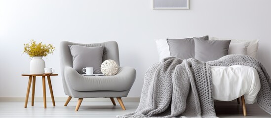 Breakfast tray on a comfortable bed in a chic, white bedroom with a modern gray armchair.