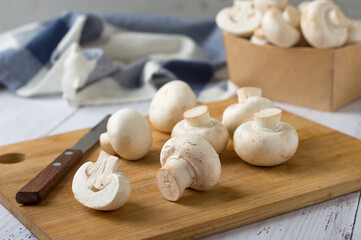 Champignons on a cutting board, knife, kitchen towel. Cooking process, cutting mushrooms. Horizontal, free space for copying.