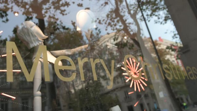 Commemorating the Christmas season, a sticker on a glass window with LED fireworks animation in the background is seen at a fashion retail shop with the message "Merry Christmas".