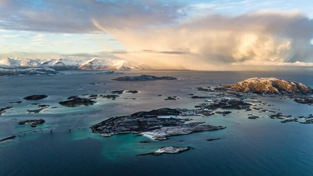 aerial hyper lapse over sommaroy island village in blue water with epic storm clouds during sunirse with mountains on background in norway