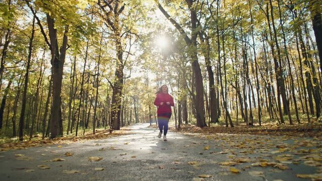 Sprint into Fall: Empowering Women's Health through Sporty Runs in the Autumn Park. High quality 4k footage