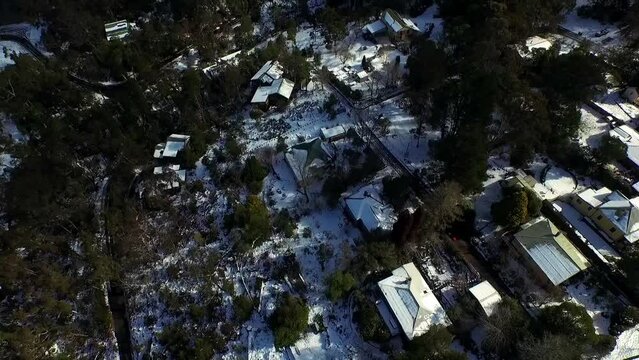Experience the charm of Blue Mountains' roof houses blanketed in rare snow&mdash;a captivating aerial view showcasing the town's picturesque, snow-covered landscape.