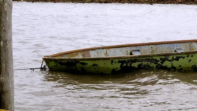 Weathered boat drifts in the harbor and is moved by waves.