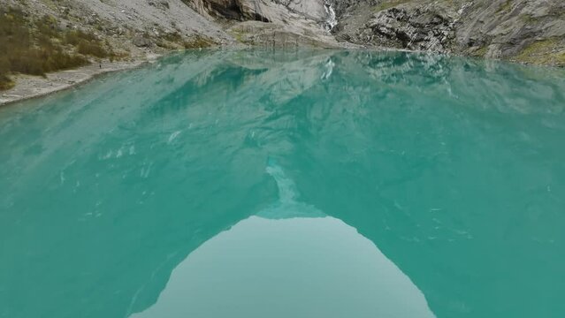 aerial view over blue lake towards briksdalsbreen glacier in norway with reflecting mountains in water