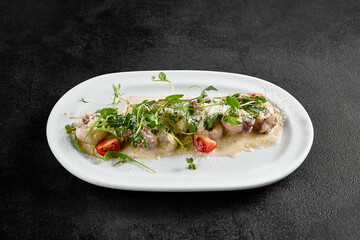 Creamy seafood assortment garnished with fresh greens and cherry tomatoes on a white oval plate