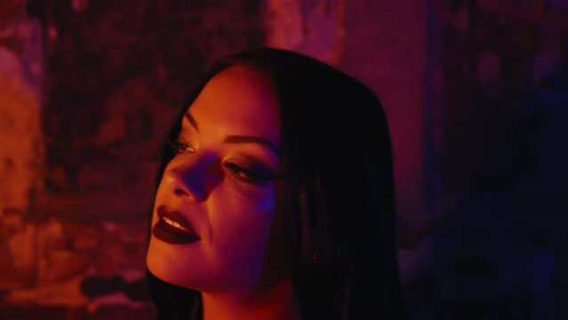 A beautiful goth women looking at Christmas sparkles in her hand, dark makeup and a Halloween costume. The enchanting scene unfolds indoors during nighttime.