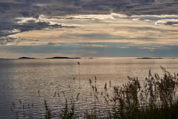 Landscape picture of the calm water, long shadows and midnight sunlight in the Norwegian fjord in...