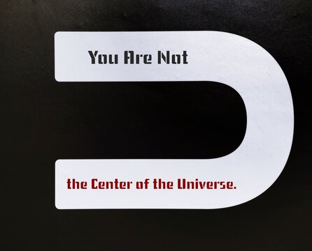 Black wall with U letter and text inscription YOU ARE NOT THE CENTER OF THE UNIVERSE, to remind we are not focus of everyone attention, we are much more focus of ourselves mistakes and flaws