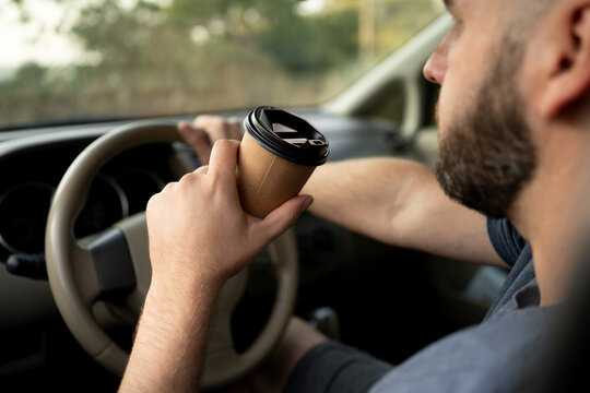 Bearded Man Driving Holding A Paper Coffee Cup To Not Sleepiness.