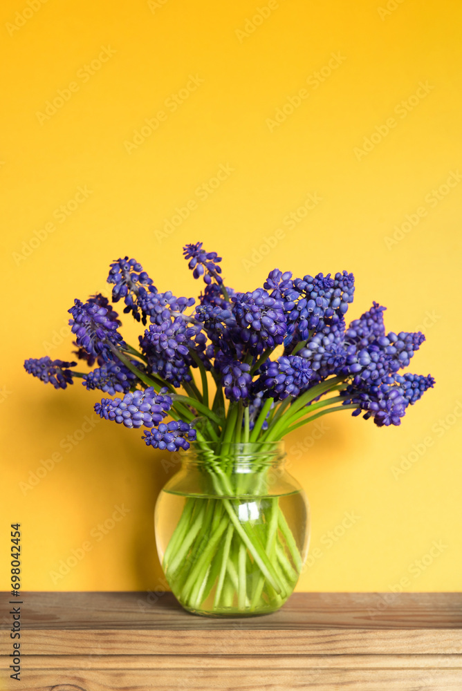 Poster  Minimal floral arrangement of a bouquet of blue flowers in a transparent vase on yellow. Happy mother's day, birthday, wedding composition. Blank greeting card, invitation and mockup.