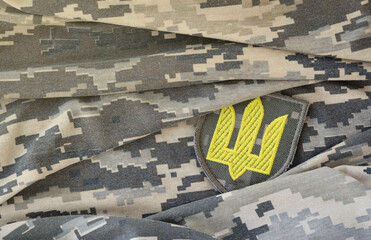Symbol of Ukrainian army on the camouflage uniform of a Ukrainian soldier. The concept of war in...