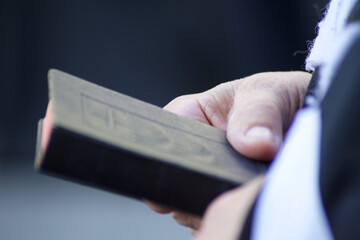 close up of an holy book with red sheets in hands of a clerical person