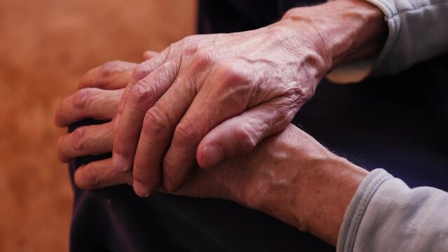 close-up of folded wrinkled veiny hands of an elderly man. retirement age. an impersonal elderly man sits alone while inside.