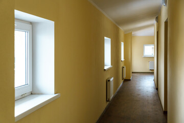 A long empty corridor in an office building. A new modern heating radiator on a white wall. Large...