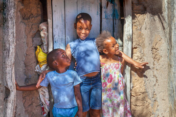 portrait of group of african children in the village, standing in front of door of the hut in an...