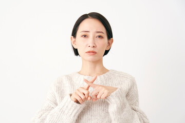 指でばつ印のジェスチャーをする中年女性　白背景