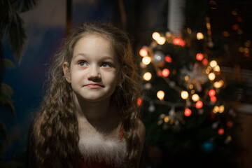 A little girl with a beautiful smile. Blond Haired Child Celebrating Christmas with Festive Decorations and Tree. Soft selective focus. 