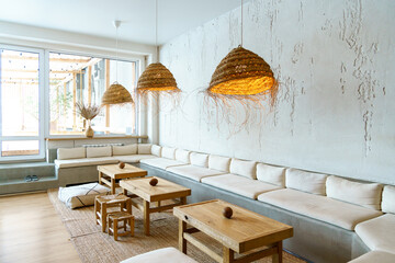 Unusual designer chandeliers made of straw. A spacious and cozy living room with upholstered sofas,...