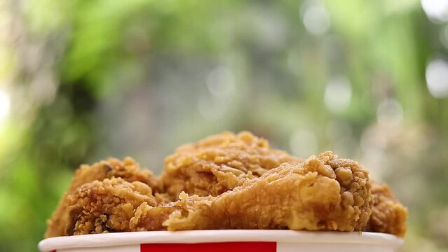 Bucket filled with crispy Kentucky fried chicken with smoke on nature background