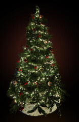 Christmas tree with decorations and garlands with lights on a dark background