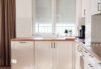 Interior of kitchen and dining room, white kitchen cabinetry and steel appliances. Interior photography. Open space living room with kitchen