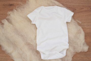Mockup of white baby bodysuit on wood background. Blank baby clothes template mock up. Flat lay...