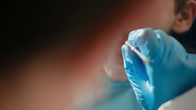 Caring female dentist using dental probe and angled mirror while doing tooth decay status on a young patient

