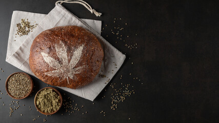 Fresh baked loaf of spelt sourdough bread with crushed hemp seeds is decorated with cannabis leaf...