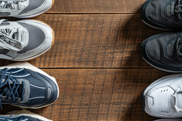 Four pairs of various sneakers on a wooden background, closeup, top view, copy space