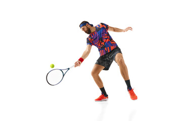 Bearded man in his 30s, tennis plater in colorful uniform practicing, returning ball with racket...