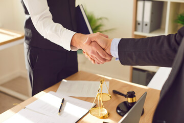 Attorney and client meet in a handshake, symbolizing the culmination of a business agreement. Close...