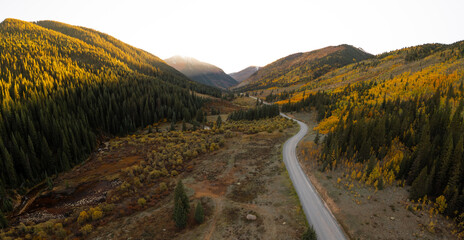 Million Dollar Highway Sun Setting in Distance. Aerial View of Mountain Road Leading Through Beautiful Forest of Aspen Trees in the Fall Season.