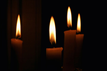 Fototapeta na wymiar Lighting the Darkness: Four Candles Illuminating a Dark Room