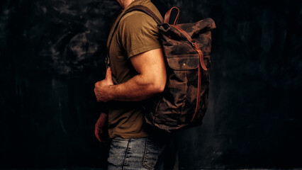 Fototapeta na wymiar Man with stylish canvas backpack on dark background, back view. Close up