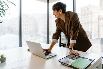 Portrait of smiling business woman working on laptop while standing in conference room