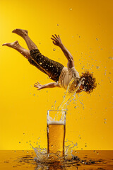 Young man falling down into glass with lager beer  - obrazy, fototapety, plakaty