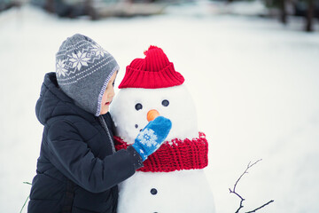 Cute little girl building snowman outdoor nature winter and playing with him. Children winter...