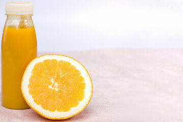 Orange juice in a glass bottle on a light background, copy space