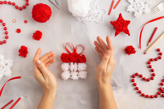Making pom-poms from red and white threads. Ideas of Christmas decoration diy with kids