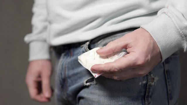 The drug addict takes out a bag of cocaine from his pocket. Heroin drug addiction concept.