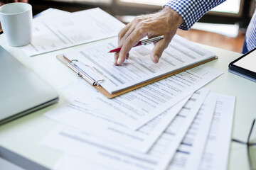 Hand of businessman or lawyer checking business contract, loan documents and other important...