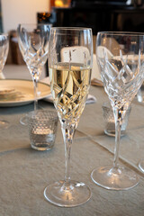 New year dinner served with champagne cava or prosecco wine in crystal glasses on table with christmas tree and garland lights on background