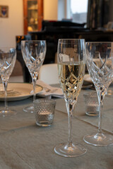 New year dinner served with champagne cava or prosecco wine in crystal glasses on table with christmas tree and garland lights on background