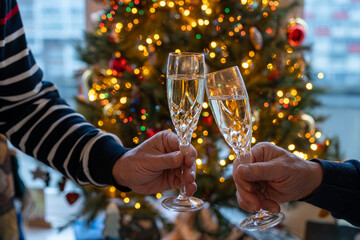 New year or christmas dinner, two man hands with glasses of champagne cava or prosecco wine crystal...