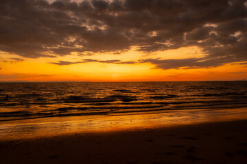 Obraz premium The sea when the sun is about to set The entire horizon is yellow and the foreground is black so that the background is clearly visible.