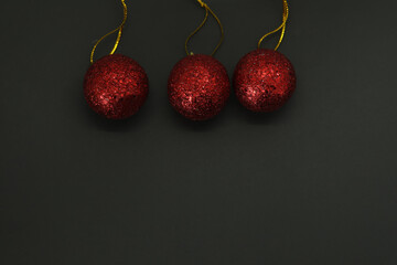 Three red christmas baubles on black background with copy space for your text