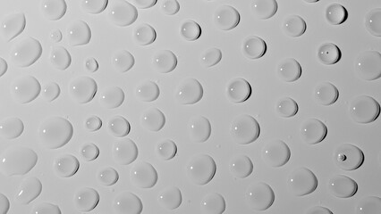 Many large shiny water droplets on glass on white studio background. Water splashes of rain. Aqua particle creative advertising concept.