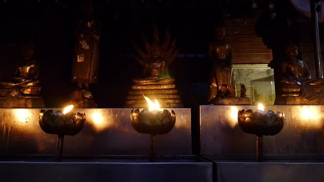 Light a candle in front of the Buddha statue, Candles burning around in area of front Buddha statue