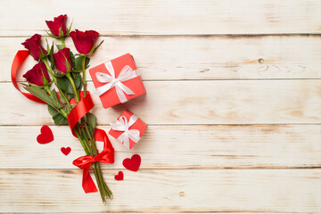 Red rose flowers with gift box on wooden background, top, view. Valentine's day concept
